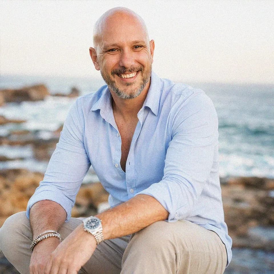 Dustin Steller sitting on a rocky coastline by the sea