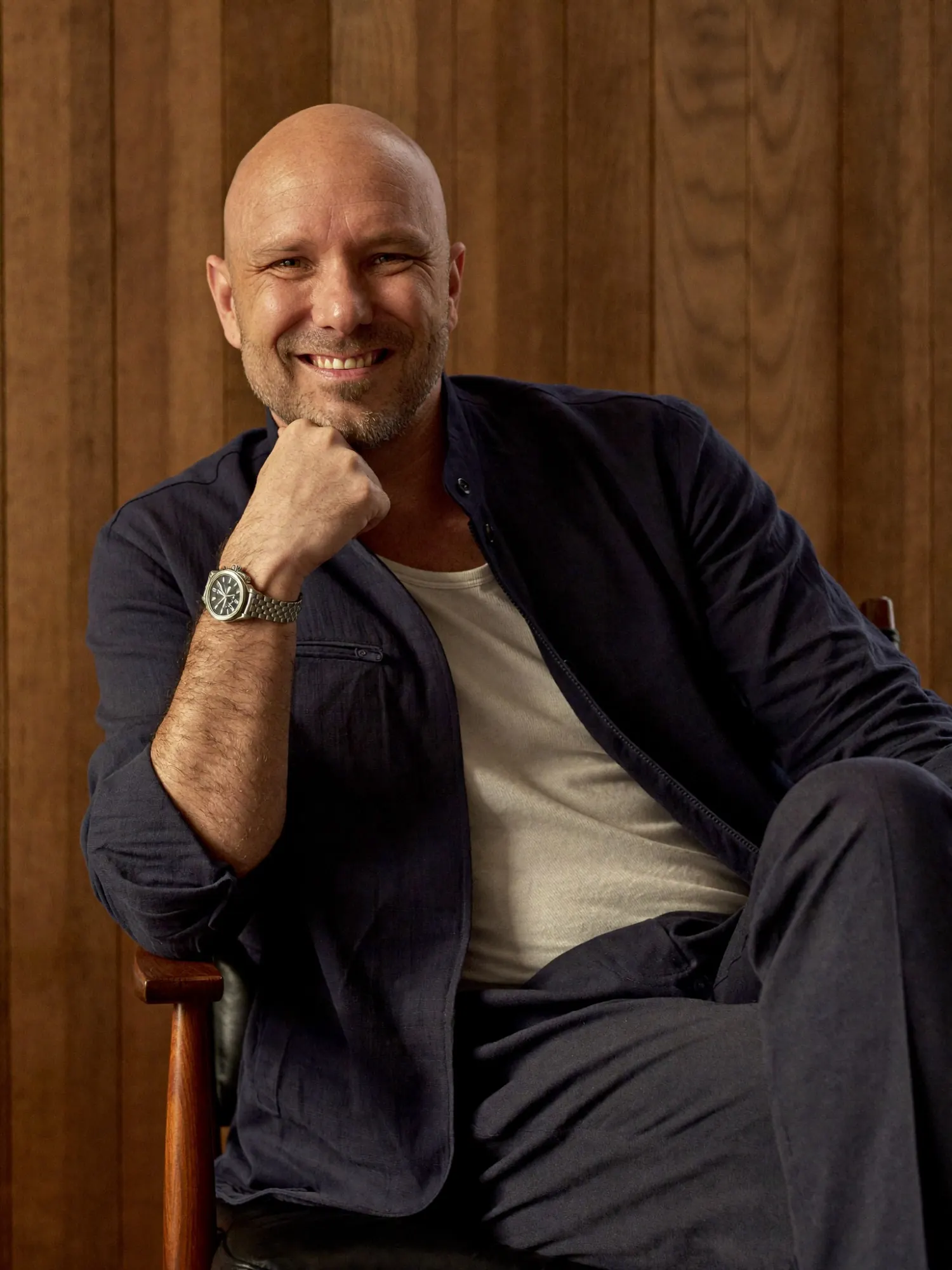 Dustin Steller, smiling, seated in front of a walnut-paneled wall